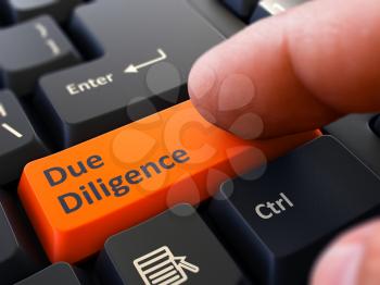 Due Diligence - Written on Orange Keyboard Key. Male Hand Presses Button on Black PC Keyboard. Closeup View. Blurred Background.