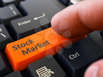 Stock Market Orange Button - Finger Pushing Button of Black Computer Keyboard. Blurred Background. Closeup View.