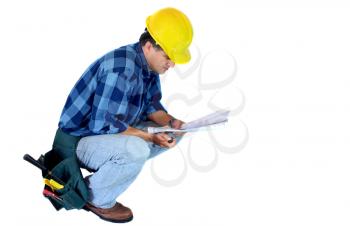 Contractor kneeling reading a blueprint isolated on white