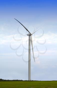 Wind turbine generator in a green meadow against a natural sky