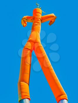 Orange inflatable man on blue sky background