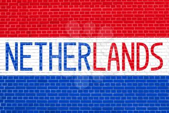 Flag of the Netherlands on brick wall texture background. Word Netherlands.
