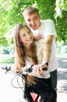 A young couple sitting on a bicycle