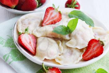 Dumplings with fresh strawberries, cream and mint