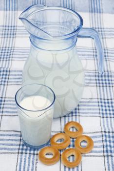 Milk in jug and glass with bagels on tablecloth