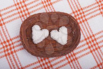 Cookies in the form of hearts in the basket on the tablecloth.