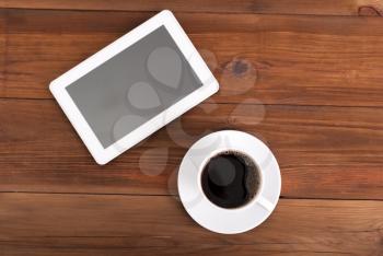 Cup of coffee and tablet on the table. Top view .