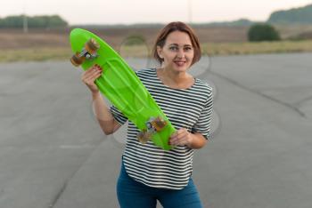 Cheerful young girl with a skateboard in hands.