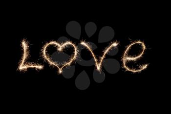 Love word written by sparklers on a black background.