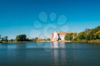 Mir, Belarus. Scenic View Of Mir Castle Complex From Side Of Lake. Architectural Ensemble Of Feudalism, Ancient Cultural Monument, Unesco Heritage. Famous Landmark In Summer Sunny Day Under Blue Sky