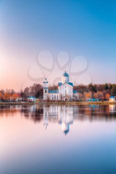 Alexander Nevsky Orthodox Christian Church With Bell Tower And Chapel On Lake Shore In Sunset Sunrise Dawn, Early Spring, Forest Park Background. Gomel, Homiel, Belarus