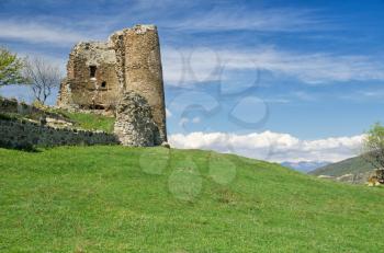 Ruin of medieval fortress sitting on grassy hill. Georgia