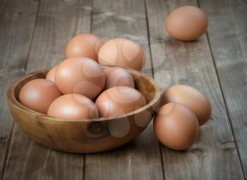 eggs in a wooden bowl on the table from the old boards