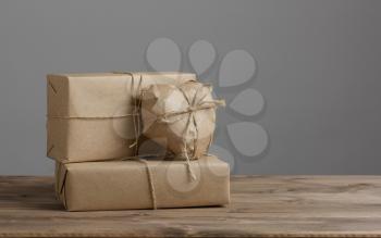 Heart and box wrapped in brown kraft paper on wooden table and grey background