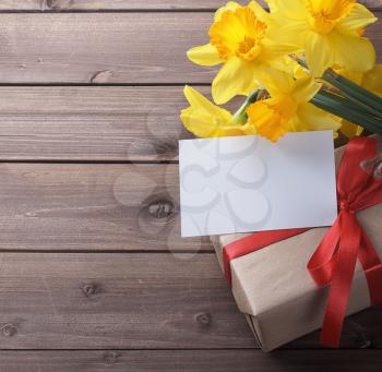 daffodils with gift box with a note on a wooden table