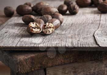 whole and chopped pecan nuts on old wooden table. 