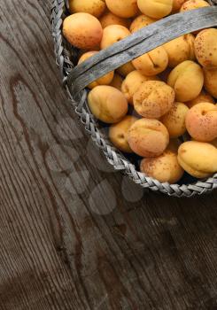Full basket with ripe apricots on a wooden table