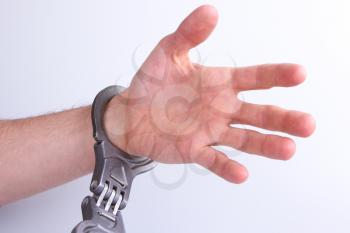 A man in metal handcuffs on a grey background