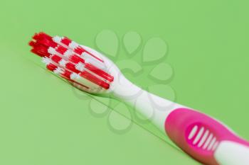 A pink toothbrush on a green background