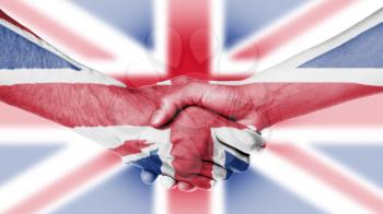 Man and woman shaking hands, arms wrapped in the flag the UK