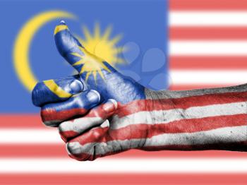 Old woman with arthritis giving the thumbs up sign, wrapped in flag pattern, Malaysia
