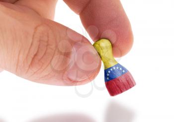Hand holding wooden pawn with a flag painting, selective focus, Venezuela