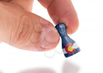 Hand holding wooden pawn with a flag painting, selective focus, Colorado