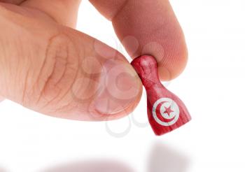 Hand holding wooden pawn with a flag painting, selective focus, Tunisia
