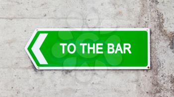 Green sign on a concrete wall - To the bar
