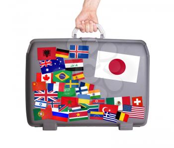 Used plastic suitcase with lots of small stickers, large sticker of Japan