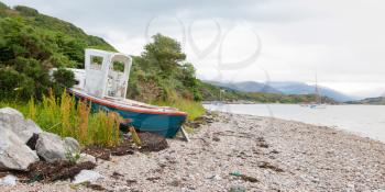 Small shipwreck at a loch with stone beach, Scotland