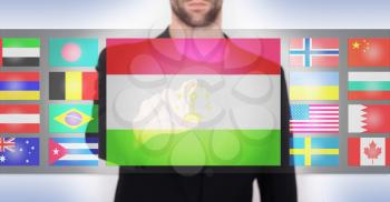 Hand pushing on a touch screen interface, choosing language or country, Tajikistan