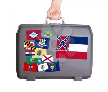 Used plastic suitcase with stains and scratches, stickers of US States, Mississippi