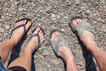 Adult couple with slippers standing on a stone beach