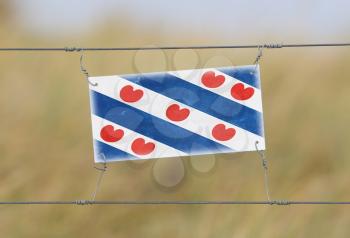 Border fence - Old plastic sign with a flag - Friesland