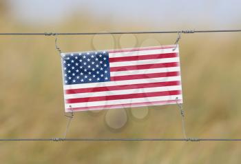 Border fence - Old plastic sign with a flag - USA