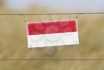 Border fence - Old plastic sign with a flag - Indonesia