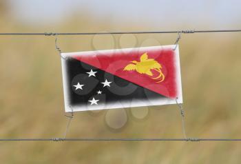 Border fence - Old plastic sign with a flag - Papua New Guinea