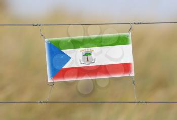 Border fence - Old plastic sign with a flag - Equatorial Guinea