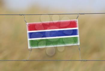 Border fence - Old plastic sign with a flag - Gambia