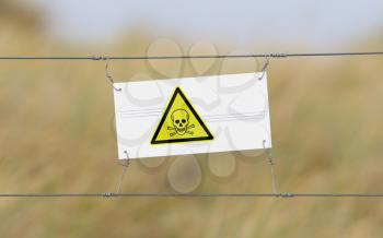 Border fence - Old plastic sign with a flag - Poison