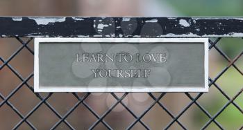 Sign hanging on an old metallic gate - Learn to love yourself