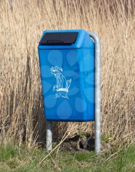Close up of bright blue dog mess poop bin with Label