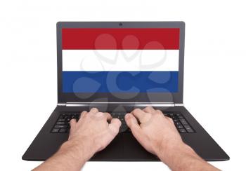 Hands working on laptop showing on the screen the flag of the Netherlands
