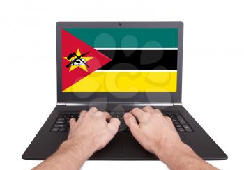 Hands working on laptop showing on the screen the flag of Mozambique