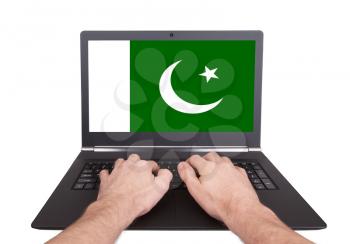 Hands working on laptop showing on the screen the flag of Pakistan