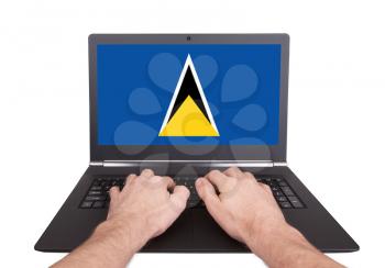 Hands working on laptop showing on the screen the flag of Saint Lucia
