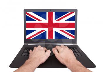 Hands working on laptop showing on the screen the flag of the UK