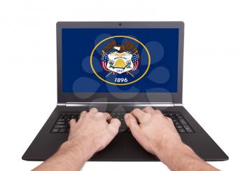 Hands working on laptop showing on the screen the flag of Utah