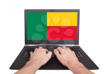 Hands working on laptop showing on the screen the flag of Benin